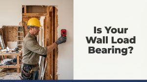 Construction worker using stud finder on interior wall to identify load bearing wall in Toronto home renovation